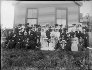 Wedding portrait of unidentified bride and groom with wedding party and family members, in the garden, at the back of the house, possibly Christchurch district