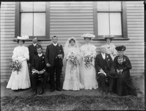 Wedding portrait of unidentified bride and groom with wedding party in the garden at the back of the house, possibly Christchurch district
