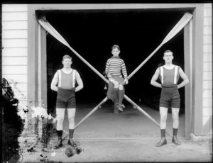 Rowing doubles team with coxswain holding rudder and sitting on crossed paddles, probably Christchurch region