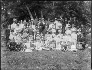 A group of unidentified men, women and children, in an unidentified park under a row of trees, possibly Christchurch district