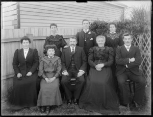 Members of an unidentified family, three men and five women, in the garden at the back of the house, possibly Christchurch district