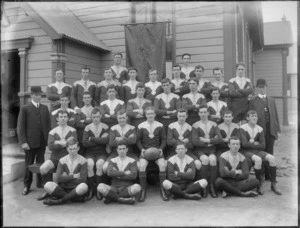 Unidentified members of the Christchurch Rugby [Union?] team, showing a banner in the background with [Marist Brothers Old Boys Association?], MBOBA, Christchurch on it, outside the hall on Barbadoes Street, Christchurch