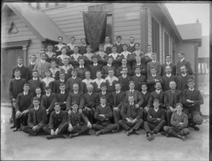 Unidentified members of the Christchurch Rugby [Union?] Club, showing a banner in the background with [Marist Brothers Old Boys Association?], MBOBA, CHRISTCHURCH on it, outside the hall on Barbadoes Street, Christchurch