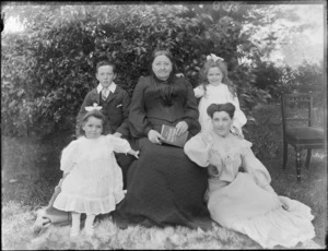 Members of an unidentified family in the garden, showing a boy and a woman sitting on chairs, a girl standing alongside the woman, a woman sitting on a rug and a girl in the front, probably Christchurch district