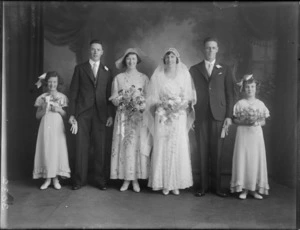 Studio portrait of unidentified bride and groom with wedding party and two flowergirls, probably Christchurch district