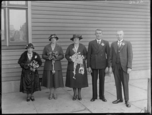 Wedding portrait of unidentified bride and groom with wedding party in front of a building, probably Christchurch district