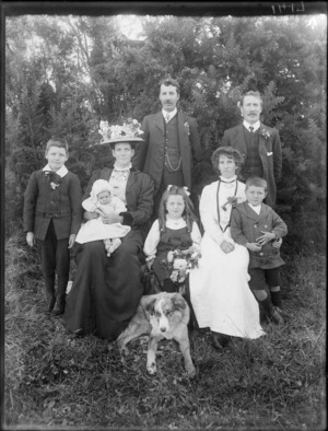 A family group portrait, showing two men, two women, two boys, a girl, a baby and a dog in the front on the grass, possibly Christchurch district