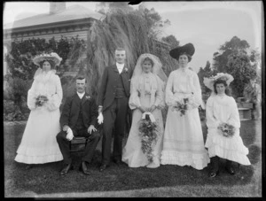 Wedding portrait of unidentified bride and groom with wedding party, in the garden of a house, possibly Christchurch disrict