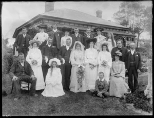 Wedding portrait of unidentified bride and groom with wedding party and family members, in the garden of a house, possibly Christchurch district