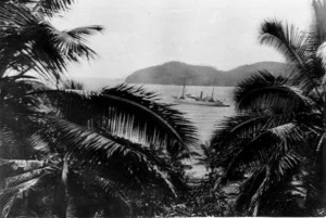 View, between palm trees, of a ship at sea in the Pacific