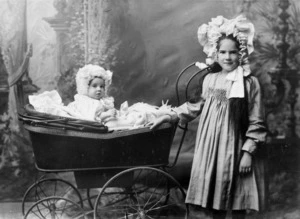 Girl, standing next to a baby in a pram