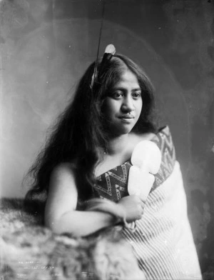 Young woman wearing a Maori cloak, holding a patu