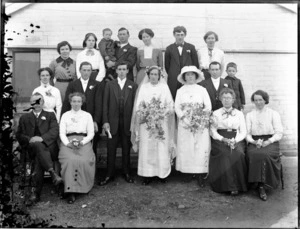 Unidentified wedding group portrait, outside a brick building, showing bride and groom with five men, nine women and two boys, probably Christchurch region
