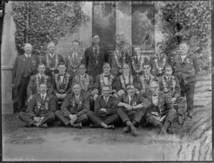 Group of unidentified men, wearing badges on their collars, outside a stone building, probably Christchurch district