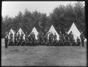 Group of unidentified young men in military cadet uniform with bayonets, with row of tents behind, probably Christchurch district