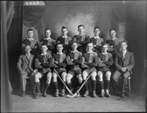 Studio portrait of unidentified men's hockey team and coaches, probably Christchurch district, includes two hockey sticks in front