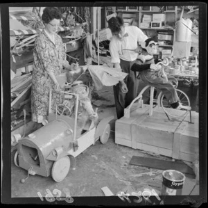 Unidentified workers preparing Christmas window display featuring a monkey on a bike and a monkey in a car, James Smith department store, Wellington