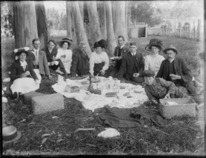 Unidentified family group having a picnic outdoors under a tree, probably Christchurch district