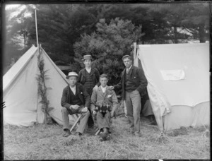 Group of unidentified male youths outside tents, probably Christchurch district, one youth has piano accordian in his lap, sign on tent reads 'Lilac Camp'