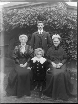 Unidentified family group outdoors, showing a man and two women, one of whom is elderly, with a small boy in a velvet suit, probably Christchurch district