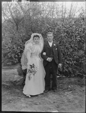 Unidentified wedding portrait taken outdoors, with groom, and bride with veil and flowers, probably Christchurch region