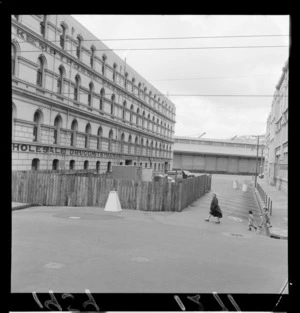 Unidentified women and two children walk past site of sewerage construction on Willeston St, Wellington, including Kempthorne, Prosser & Company Building [New Zealand Drug Company?]