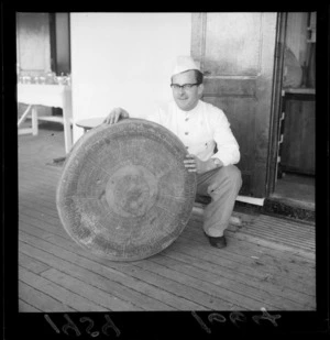 Unidentified chef holds a large wheel of cheese on board a Dutch ship