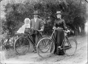 Unidentified man and woman with bicycles, a little girl is sitting in a cane seat attached to the handlebars, probably Christchurch district