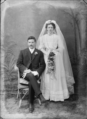 Portrait of unidentified bride and groom, with a painted studio backdrop, probably Christchurch district