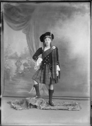 Studio portrait of an unidentified Highland dancer, showing a girl wearing traditional Scottish costume