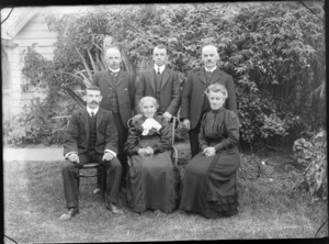 Family group, showing unidentified men and women, in a garden, possibly Christchurch