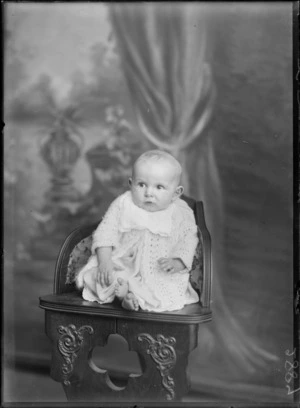 Studio portrait of unidentified young baby on highchair wearing crochet matinee top, Christchurch