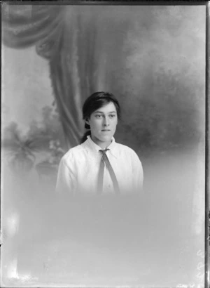 Head and shoulders studio portrait of unidentified young woman, wearing an embroidered blouse with a ribbon necktie, probably Christchurch district
