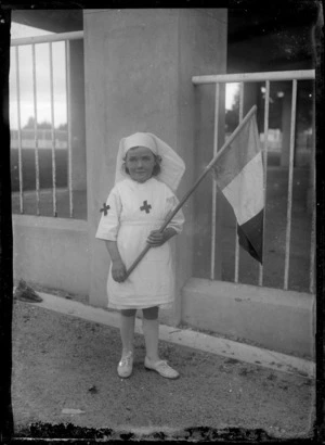 Unidentified girl dressed in a nurse's uniform holding a [French?] flag, probably Hastings district