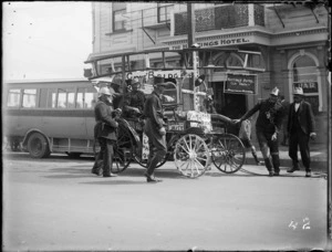 Hastings street procession, with men dressed as firemen pulling a buggy float with ladder and signs, outside the Hastings Hotel, Hawke's Bay District