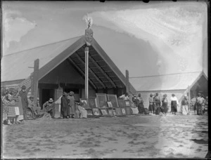 Gathering in front of meeting houses, Omahu Marae, with portraits and photos of family members, Fernhill, Hastings, Hawke's Bay District