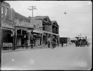 Napier earthquake damage, view of large collapsed brick buildings with workmen milling around, traction engine at the ready, 'Yates Cash Store', Napier, Hawke's Bay District