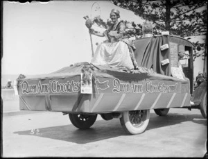 New Napier Week Carnival, woman dressed as Queen Anne on the back of a truck, with sign 'Queen Anne Chocolates, Always Fresh', Marine Parade, Napier, Hawke's Bay District