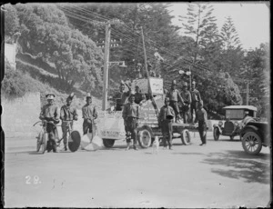 New Napier Week Carnival, men dressed in costumes with truck float and bicycles, sign with 'Dark Town Fire Brigade', Marine Parade, Napier, Hawke's Bay District