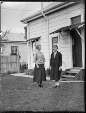 View of two women standing by the back entrance of a house, Hawke's Bay District