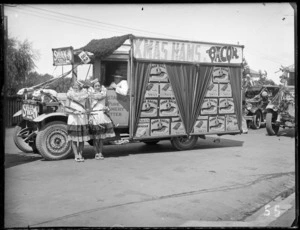 New Napier Week Carnival, view of Swan Hams' truck float with sign for 'Xmas Hams & Bacon', with 'Swan Bacon Taste Tells' boxes, two women in costumes in front, Napier, Hawke's Bay District