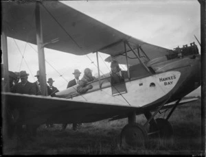 Two unidentified pilots in a biplane with men standing behind, showing Hawke's Bay written on the nose, probably Hastings district