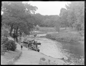 Children and women on the banks of the Avon River while men row boats on the river, Christchurch