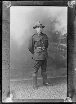 Studio portrait of unidentified young World War One soldier in uniform with 'NZ silver fern crown' collar and hat badges, Christchurch