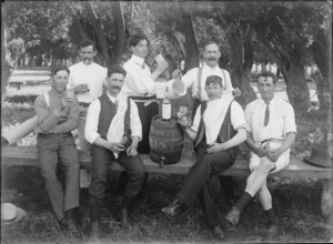 Unidentified men on a park bench with beer barrel, jug and bottle, having a drink [social outing, wedding reception?], with trees beyond, [Hagley Park?], Christchurch