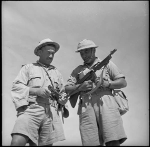 Two Maori Battalion soldiers examining captured enemy equipment, Western Desert, Egypt - Photograph taken by H Paton