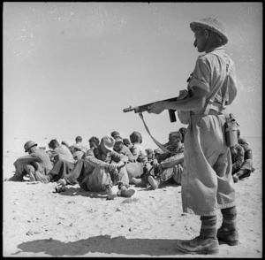 NZer with tommy gun guards POW in the Alamein area, Egypt