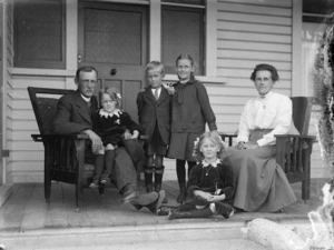 A man, a woman, and four children, on a verandah of a house
