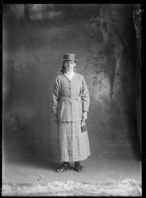 Studio portrait of an unidentified young woman wearing a wool suit and a straw boater, possibly Christchurch district