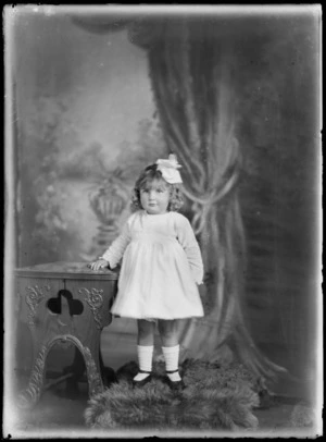 Studio portrait of an unidentified small girl, wearing a bow in her hair, possibly Christchurch district